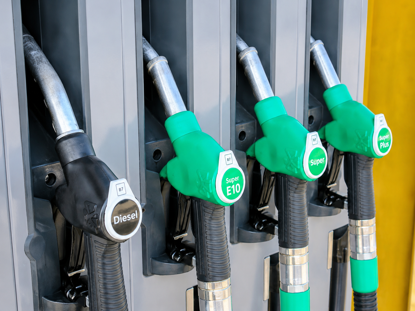 High-resolution image of diesel and petrol fuel pump nozzles at a gas station during rising global oil price concerns.